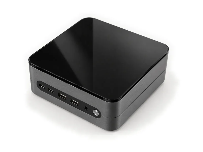 Black glass-top grey mini PC on a light studio background