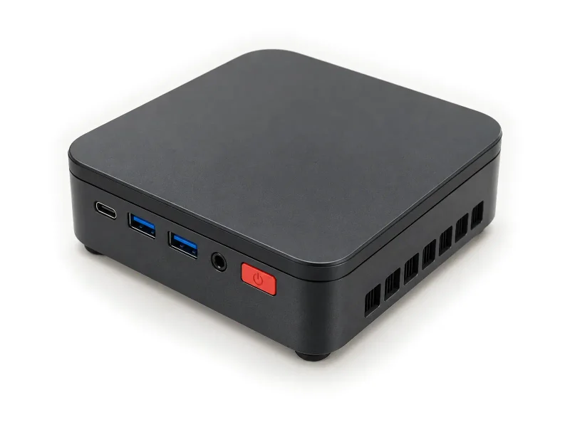 Dark compact desktop mini PC with red power button on a light studio background
