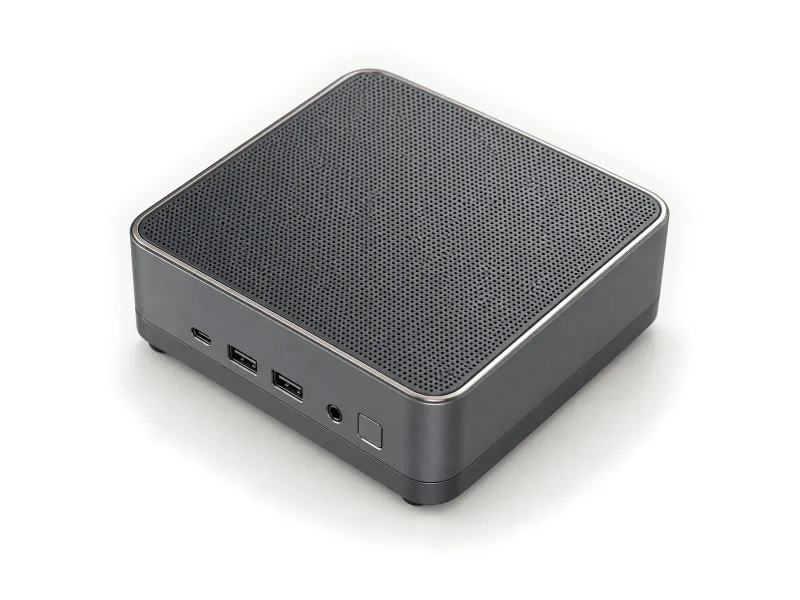 Grey mini PC with fine perforated top grille on a light studio background
